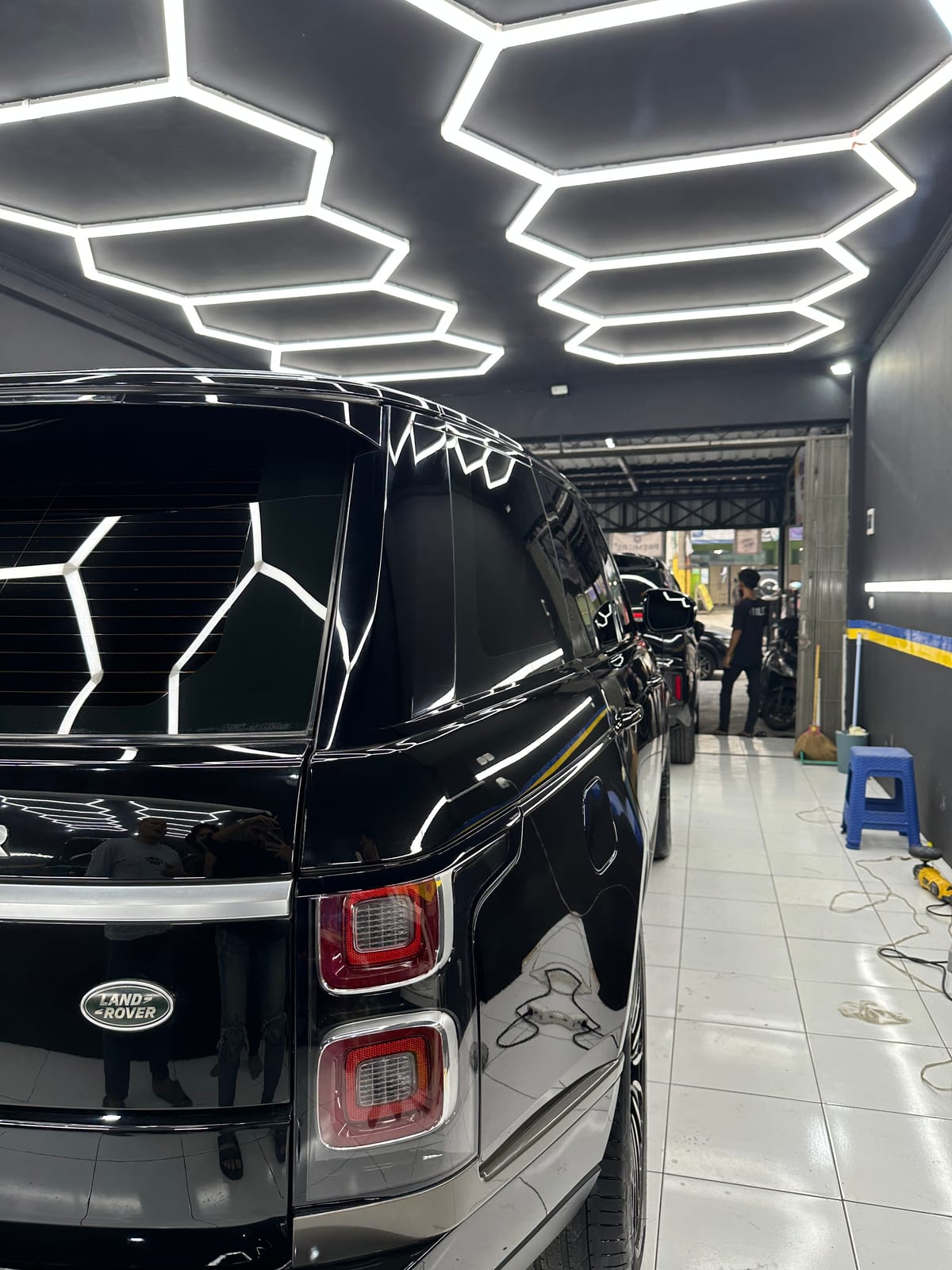 Land Rover hitam di workshop dengan lampu hexagon